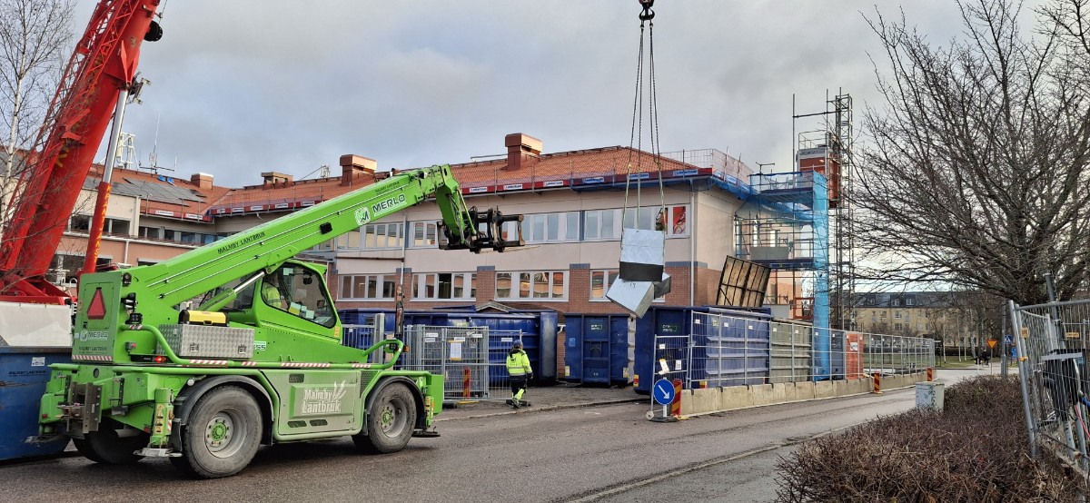 En mobilkran lyfter ut ventilationsaggregat via taket.