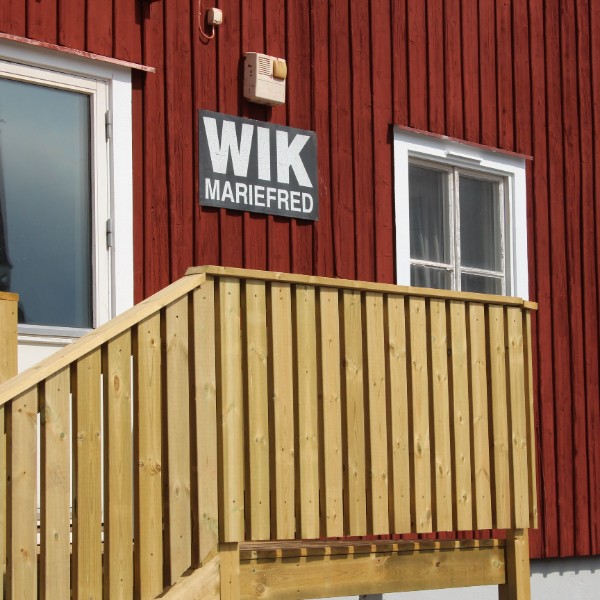 Skylt Wik Mariefred på röd fasad.
